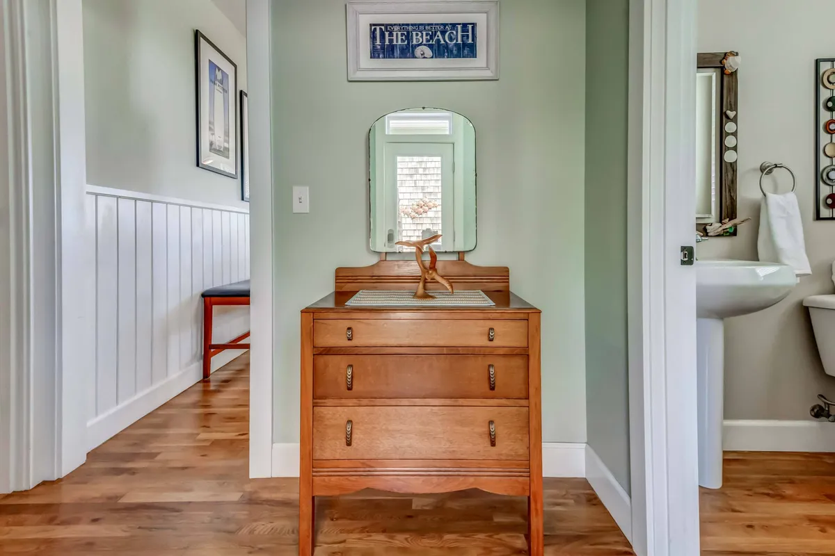 A cozy and inviting interior with a wooden dresser, mirror, and beach-themed artwork. The space feels open and designed for casual conversations, getting ready, or relaxing together before heading out to enjoy group activities.