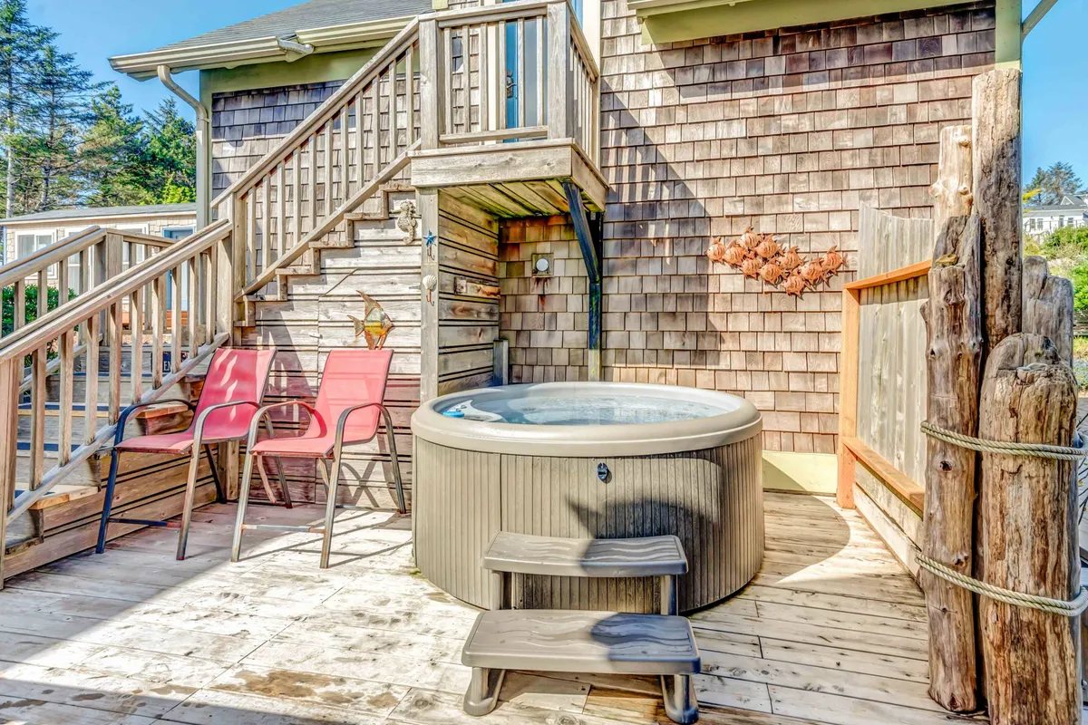 The private hot tub area is set on an exterior deck, with steps leading up to the tub and cozy outdoor seating nearby. The view stretches toward the horizon, perfect for soaking while watching the sunset or stargazing at night.